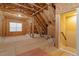 Unfinished attic space with exposed wooden beams, a window, and plywood flooring at 212 Preatonwood Dr, Apex, NC 27539
