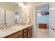 Bathroom featuring a double sink vanity with dark wood cabinets and a view into an adjacent bedroom at 212 Preatonwood Dr, Apex, NC 27539