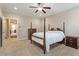 Well-lit bedroom with a four-poster bed, beige walls, and access to an adjacent hallway at 212 Preatonwood Dr, Apex, NC 27539