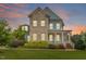 Inviting two-story home featuring a brick facade, covered porch, and lush landscaping against a colorful sky at 212 Preatonwood Dr, Apex, NC 27539