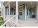 Inviting front porch with white columns, offering a glimpse of the home's stylish blue exterior and interior at 212 Preatonwood Dr, Apex, NC 27539