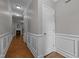 Hallway featuring hardwood floors, white trim, and access to other rooms, with a view of the living room fireplace at 238 Langford Valley Way, Cary, NC 27513