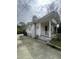 Side view of a white house featuring a covered porch, a tall chimney, and a concrete driveway at 2511 Chapel Hill Rd, Durham, NC 27707
