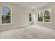 Bright bedroom with neutral carpet, natural light, and views of the landscaped exterior through multiple large windows at 2537 Cedar Hedge Ct, Apex, NC 27523