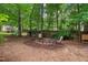 Backyard featuring a firepit, trees, mulched area, and a wooded border for privacy at 275 Eagle Stone Rdg, Youngsville, NC 27596