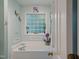 Bright bathroom showcasing a tub with jets, frosted window, tiled walls, and a calming spa-like atmosphere at 275 Eagle Stone Rdg, Youngsville, NC 27596