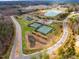 An aerial view of tennis courts, parking, and ponds within the community, surrounded by mature trees at 290 Quarter Gate Trce, Chapel Hill, NC 27516