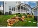 Backyard view showcasing a stone retaining wall, lawn, screened-in porch, and upper-level balcony at 290 Quarter Gate Trce, Chapel Hill, NC 27516