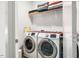 Modern laundry room with front-loading washer and dryer and upper shelf for storage at 290 Quarter Gate Trce, Chapel Hill, NC 27516