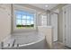 Bathroom featuring a soaking tub under a window with scenic views, plus a glass-enclosed shower at 319 Brinkley Cir, Mebane, NC 27302