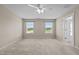 This bedroom features neutral walls, carpet, a ceiling fan, and two windows offering scenic views at 319 Brinkley Cir, Mebane, NC 27302