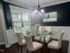 Elegant dining room with a glass table, white chairs, a decorative chandelier, and navy accent wall at 319 Brinkley Cir, Mebane, NC 27302