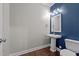 Stylish half-bath with pedestal sink, wood flooring, modern fixtures, and a blue accent wall at 319 Brinkley Cir, Mebane, NC 27302