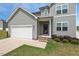 Inviting home exterior with stone accents, a well-kept lawn, and a convenient two-car garage at 328 Avery Meadows Dr, Smithfield, NC 27577