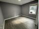 A clean bedroom featuring gray walls, white trim, a window, and modern vinyl flooring at 3825 Old Coach Rd, Raleigh, NC 27616