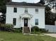 Two-story home with white siding, a black front door, chimney, and mature landscaping at 3825 Old Coach Rd, Raleigh, NC 27616