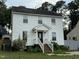 Two-story home with white siding, a black front door, chimney, and mature landscaping at 3825 Old Coach Rd, Raleigh, NC 27616