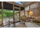 Covered sunroom showcasing wicker furniture, table lamp, and view of the brick patio and yard at 3919 Wentworth Dr, Durham, NC 27707