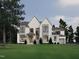 Stunning white brick home featuring grand windows, gray accents, and a well-manicured lawn at 413 Shinleaf Pond Trl, Raleigh, NC 27614