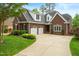 Attractive brick home with dormer windows above the garage featuring a well-manicured lawn and curved driveway at 498 Mountain Laurel, Chapel Hill, NC 27517