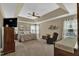 Spacious primary bedroom with tray ceilings, ceiling fan, sitting area, and ample natural light at 609 Redford Place Dr, Rolesville, NC 27571