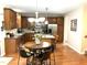 Open concept kitchen featuring stainless appliances, wooden cabinets, a large island with seating and hardwood floors at 609 Redford Place Dr, Rolesville, NC 27571