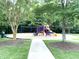 Well-maintained playground with slides, swings, and climbing structures, surrounded by lush greenery and a sidewalk at 609 Redford Place Dr, Rolesville, NC 27571