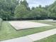 Sandy volleyball court with a net, surrounded by green grass and a sidewalk, perfect for outdoor games and activities at 609 Redford Place Dr, Rolesville, NC 27571