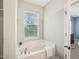 Bathroom featuring a soaking tub with a towel and window; the Primary bedroom is in the background at 611 Ashbrittle Dr, Rolesville, NC 27571