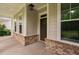 Covered porch with brick and siding exterior and a dark wood door at 623 Cabin Crk, Pittsboro, NC 27312