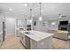 Open-concept kitchen with a large island, quartz countertops, stainless steel appliances, and seamless flow into the living area at 623 Cabin Crk, Pittsboro, NC 27312