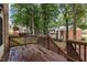 Inviting back deck with wood flooring, railings, and a table for outdoor relaxation and entertaining surrounded by mature trees at 6423 New Market Way, Raleigh, NC 27615