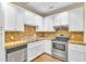 Well-lit kitchen featuring stainless steel appliances, granite counters and white cabinets and hardwood floors at 6423 New Market Way, Raleigh, NC 27615