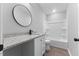 This bathroom boasts a vanity with granite countertop, white cabinetry and modern round mirror at 714 Harriett St, Henderson, NC 27536