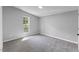 A bright bedroom features neutral walls, plush carpeting and a window letting in natural light at 714 Harriett St, Henderson, NC 27536