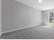 A bright bedroom features neutral walls, plush carpeting and a window letting in natural light at 714 Harriett St, Henderson, NC 27536