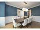 Well-lit dining room with a dark wood table, bright white chairs, and a modern light fixture at 7736 Roberts Rd, Apex, NC 27523