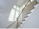 Elegant staircase featuring white risers, natural wood handrail, and expansive windows flooding the area with light at 7736 Roberts Rd, Apex, NC 27523