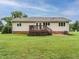 View of the home's backyard featuring a wooden deck, patio with bench, and a well-maintained green lawn at 8204 Charlbert Ct, Apex, NC 27539