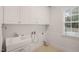 Bright laundry room featuring white cabinets, tile floor and a window at 85 Pebble Creek Dr, Franklinton, NC 27525