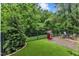 Landscaped backyard with a patio, grill, lush greenery, and a manicured artificial turf area at 8611 London Park Ct, Raleigh, NC 27615