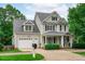 Attractive two-story home with a well-kept lawn, inviting porch, black shutters, dormer windows, and an attached garage at 1004 Manderston Ln, Apex, NC 27502