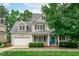 Charming two-story home with a manicured front lawn, attached garage, dormer windows and a welcoming blue front door at 1004 Manderston Ln, Apex, NC 27502