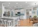 Open kitchen boasts white cabinetry, stainless appliances, island with seating, and adjacent breakfast nook at 1004 Manderston Ln, Apex, NC 27502