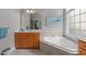 Bright primary bathroom with a corner tub, wooden vanity, and serene artwork at 1004 Manderston Ln, Apex, NC 27502