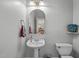 Classic powder room featuring a pedestal sink, decorative mirror, and colorful hand towel at 1004 Manderston Ln, Apex, NC 27502