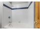 Tiled shower and bathtub with coordinating blue accent tiles, complemented by wooden door at 1008 Dorothea Dr, Raleigh, NC 27603
