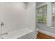 Bathroom with white tile bathtub and shower, and window with blinds at 1008 Dorothea Dr, Raleigh, NC 27603