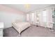 Bedroom with a bed, side table, pink walls, carpet, board and batten trim, and multiple windows at 102 Michelangelo Pl, Morrisville, NC 27560