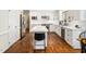Bright kitchen features white cabinetry, stainless appliances, island with quartz countertop, and hardwood floors at 103 Lochwood West Dr, Cary, NC 27518